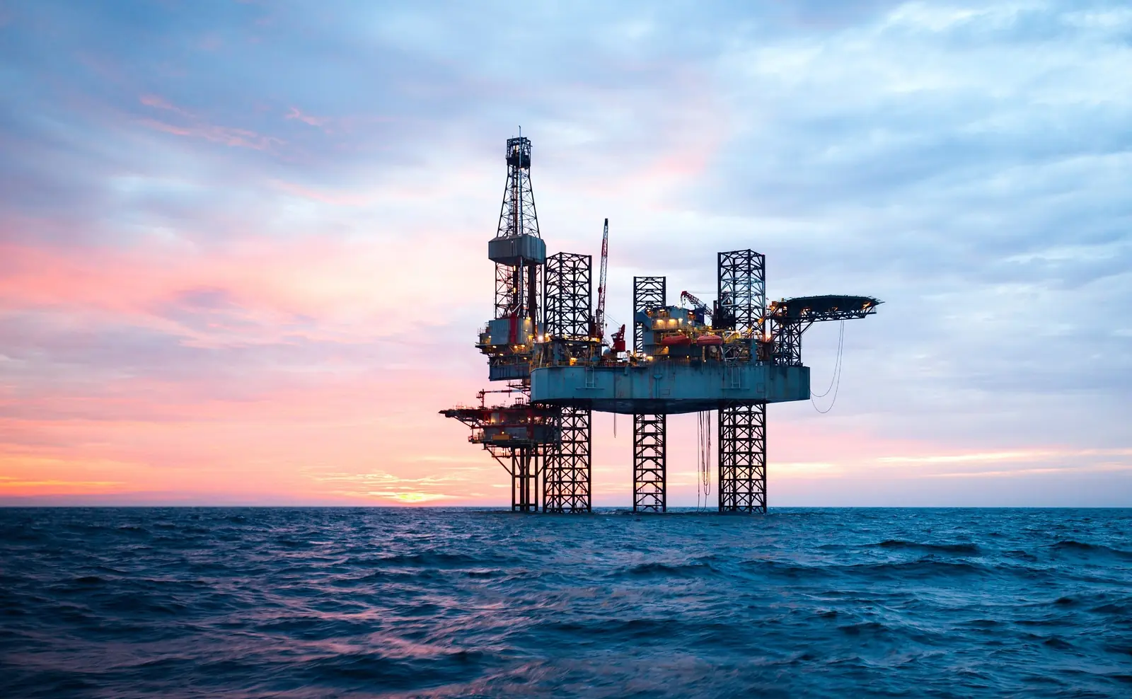 Jack-up drilling rig operating offshore at sunset